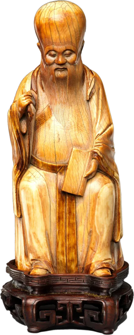 寿星象牙坐像:额头高耸、长须垂胸的老人,一手抬到肩前,一手按着膝上的一册书,坐在雕花木座上
