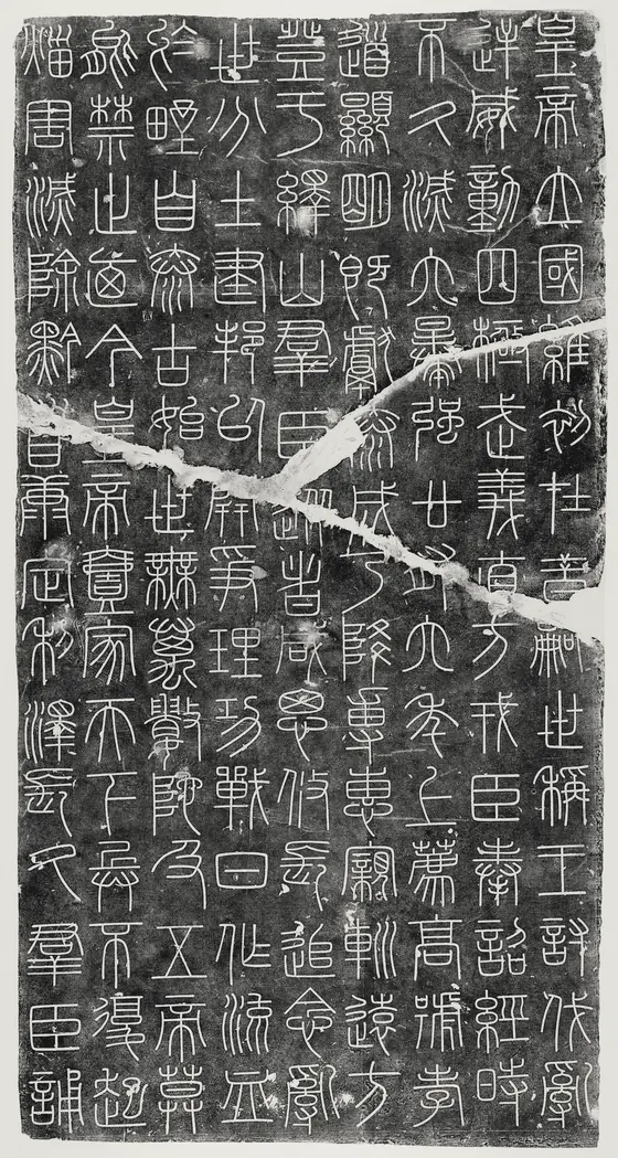峄山刻石拓片:黑底上一行行白色的小篆,石面有横贯的裂痕