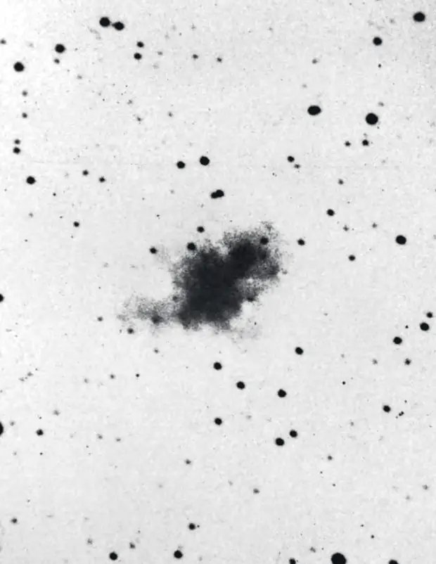 蟹状星云的老照片，以负片显示：白底上一团不规则的黑色星云，周围散着黑色的星点